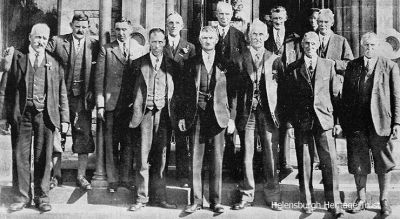 Flower Show officials
Officials and judges on the steps of the Victoria Hall before the August 1933 Helensburgh and Gareloch Horticultural Society Show. Back row from left: William Gow, J.Wilson, hon secretary A.L.Chapman, J.Davidson, J.Johnston, J.Christie; front: S.McLean, J.Struthers, F.Burns, J.Hill, parks superintendent Alex Campbell, J.Smellie. Image from Helensburgh and Gareloch Times.
