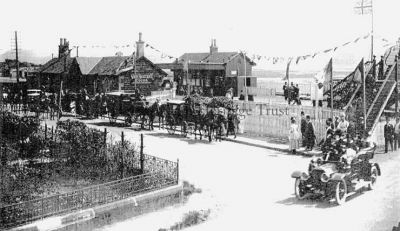 Cardross Station
A picture of a mystery celebration at Cardross Station. The bunting and Union Jacks, the waiting horse drawn carriages â€” and one early car â€” and the finery of the people in suggests a very special occasion, perhaps the opening of part of the station, or troops returning from the First World War, or even a royal visit? However it is believed to be the arrival of guests attending a wedding. The station was opened on January 15 1858, the line was doubled in 1883, and the bridge was built the following year.
