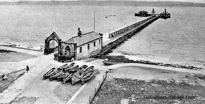 Helensburgh Pier
An unusual picture of Helensburgh pier, c.1908, before the outdoor swimming pool was built in 1928 on the left of the entrance arch. Men and children can be seen standing around, while the fishing boats are ready to be launched. Image circa 1905.
