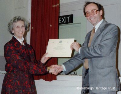 Scroll awarded
The doyen of Scottish country dancing in Helensburgh, Norah Dunn, pictured receiving the Royal Scottish Country Dance Society scroll from Alan Carrie in November 1989. Image supplied by Anne Thorn.
