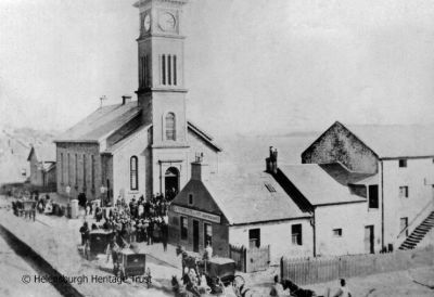 Old Parish Church
Parishioners arrive for a service at the Old Parish Church on the seafront. Next door is the Granary, at that time run by R.S.McFarlane & Son, Grain Merchants. Image, date unknown, supplied by Malcolm LeMay.
