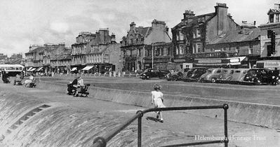 Pier car park
The Helensburgh pier car park is fairly empty as a young girl returns to her parents. Image, date unknown, by Macneur & Bryden Ltd. of Helensburgh.
