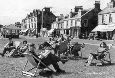 Relaxing
The sun is shining on Helensburgh's west esplanade in this picture from the past. A now demolished shelter is on the left, and on the other side of West Clyde Street is John Street. Eman's Shop, the home of Helensburgh toffee, can be seen. Image date unknown.
