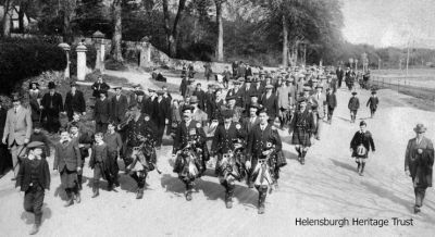 Marching to Rhu
The Helensburgh Citizen Training Force marches past Pier Road, Rhu, led by members of the Helensburgh Clan Colquhoun Pipe Band, during World War One. Image supplied by Eric McArthur who suspects the gentleman on the grass verge with the black suit and black hat and walking stick could be his grandfather, Alexander Macarthur, who lived at 56 John Street. The object of the Citizen Training Force was to provide military training for men ineligible for business or other valid reasons to enlist in the Forces.
Keywords: Parade to Rhu