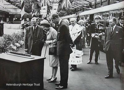 1965 Royal visit
The Queen and the Duke of Edinburgh are pictured in Helensburgh Central Station admiring a model of the first 'Blue Train' which was a gift for Prince Andrew. The Blue Trains were introduced into service on the Helensburgh-Glasgow line in 1960. The 15 minute visit was on Monday June 28 1965 when the royal couple were on their way to open new County Council offices at Garshake in Dumbarton, and the royal couple arrived at and left Clydebank on the royal yacht Britannia. Behind them are Provost J.McLeod (Cloudy) Williamson and the Lord Lieutenant of Dunbartonshire, Admiral Sir Angus Cunninghame Graham.
Keywords: Garshake, Blue Train, Royal Visit,