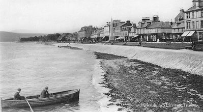 Rowing boat at pier
One of the many rowing boats which used to be kept at Helensburgh comes ashore on the seaweed-covered beach just beside the pier. Image circa 1910.
