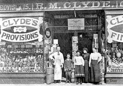 Clyde Grocery
Robert McIntosh Clyde, owner of the R.M.Clyde grocery at 64 and 66 West Princes Street, Helensburgh, is pictured outside the shop with members of his family. The red sandstone building was called Waverley Place, and was designed by Robert Wemyss and built in 1897, opposite the Post Office. His brother was Scotland's leading actor of his time, John Clyde. Image supplied by his great grandson, Alistair Paton.

