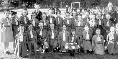 Coronation Brownies
The 3rd Helensburgh Brownie Pack pictured with Brown Owl Marion Gillies (nee Dixon), back left, at the Queen Elizabeth II Coronation celebrations at the Hermitage School playing fields at Ardencaple in June 1953, attended by all the town youth groups. The toadstool, which they sang and danced around, was made by her husband-to-be whom she had just met. Image supplied by Marion Gillies.
