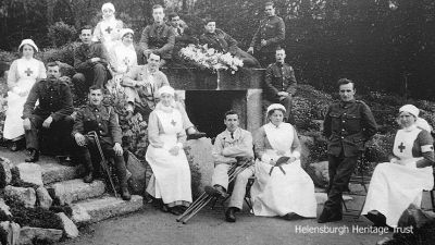 At the Wishing Well
During World War One from 1914-18 the Helensburgh Town Council-owned Hermitage House in Hermitage Park became a military hospital with a capacity for 58 patients who were sent from Stobhall Hospital in Glasgow. The wounded men in their blue uniforms were a familiar sight in the town, being wheeled around the park by their nurses. A number of local ladies and girls helped out in the hospital and the local Red Cross detachment also assisted the trained nurses. Here some of the patients and staff are seen posing beside the Wishing Well in Hermitage Park. Image date unknown.
