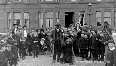 Dancing bear
Excited youngsters surround a dancing bear, brought to publicise a circus visit, on Clyde Street. Image, date unknown, supplied by Malcolm LeMay.
